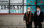 Des hommes portant des masques de protection passent devant un tableau d'indices boursiers, le 10 mars 2020 à Tokyo
