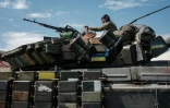 Un soldat ukrainien assis sur un char transporté par un camion près de Bakhmut, dans l'est de l'Ukraine, le 12 mai 2022