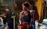 Yeimy Martinez transporte un seau d'eau pour cuisiner, le 26 mai 2020 à Bogota, en Colombie