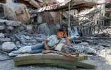 Un garçon palestinien se repose dans les décombres de Khan Younès, dans le sud de la bande de Gaza, le 10 octobre 2025.

