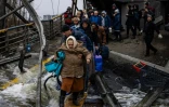 Un homme aide une femme à traverser un pont détruit pour quitter la ville d'Irpin, au nord-ouest de Kiev, le 7 mars 2022.