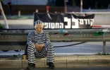 Un manifestant porte un masque représentant le Premier ministre israélien Benjamin Netanyahu vêtu d'un uniforme de prisonnier lors d'une manifestation appelant à la libération des otages dans la bande de Gaza,  à Tel-Aviv, le 15 mars 2025