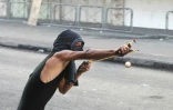 Un Palestinien tire au lance-pierre contre des forces de sécurité israéliennes, le 21 octobre 2015 à Hébron