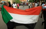 Des femmes soudanaises manifestent contre le Conseil militaire de transistion brandissant le drapeau national le 30 juin 2019 dans le centre de Khartoum