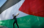Un jeune homme pose devant le drapeau palestinien le 12 octobre 2017 dans la ville de Gaza