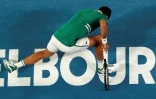 Le Serbe Novak Djokovic tombe en tentant de frapper un retour contre l'Américain Taylor Fritz au 3e tour de l'Open d'Australie, à Melbourne, le 12 février 2021