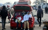Des déplacés palestiniens  attendent près du passage de Netzarim, qui coupe la bande de Gaza en deux, avant de pouvoir regagner le nord du territoire, le 26 janvier 2025
