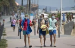 Des promeneurs avec les masques le long de la plage à Barcelone, le 18 juillet 2020