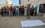 Des personnes se recueillent devant le corps d'une personne tuée la veille alors qu'elle tentait d'obtenir de l'aide à un point de distribution près du poste frontière de Zikim sous contrôle israélien, lors d'un service funèbre à l'hôpital Al-Chifa de Gaza, le 24 juin 2025