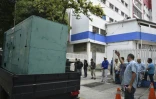 Des ouvriers de la compagnie d'électricité nationale CORPOELEC arrivent dans un hôpital pour enfants de Caracas avec un générateur durant la gigantesque panne d'électricité affectant le Venezuela le 8 mars 2019