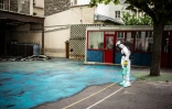 Un employé pulvérise un gel sur le sol de la cour de l'école Saint-Benoßt, prÚs de Notre-Dame de Paris, pour réduire les risques de contamination au plomb, le 8 août 2019
