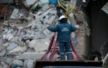 Un secouriste guide l'opérateur d'une grue qui enlève les gravats de l'immeuble partiellement effondré, le 2 janvier 2019