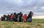 Des femmes et des enfants attendent d'être fouillés par les combattants des Forces démocratiques syriennes, après avoir quitté le dernier réduit du groupe Etat islamique à Baghouz, dans l'est de la Syrie, le 27 février 2019