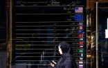 Une Iranienne marche devant un bureau de change, à Téhéran le 22 février 2026