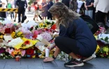 Une femme allume une bougie après avoir déposé des fleurs, le 14 avril 2024, en hommage aux victimes de l'attaque au couteau dans un centre commercial à Sydney