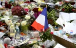 Un drapeau français parmi les fleurs et bougies déposées devant la salle du bataclan à Paris le 16 novembre 2015