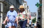 Des passants marchent dans une rue de Nantes alors qu'un thermomètre de pharmacie affiche 36 degrés, le 19 juin 2025
