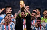 Le joueur argentin Lionel Messi (c), entouré par ses coéquipiers, soulève la Coupe du monde de football remportée par l'Argentine face à la France aux tirs aux but, le 18 décembre 2022 au stade Lusail, au Qatar