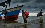 Des pêcheurs du village de Lancok, dans la région d'Aceh en Indonésie, le 25 juin 2020, aident des réfugiés rohingyas à débarquer, après une longue dérive en mer