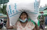Une femme porte un sac de riz distribué par le PAM à Rangoun le 21 mai 2021