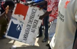 Des manifestants nigériens hostiles à la France portent une pancarte arrachée sur la façade de l'ambassade de France au Niger, à Niamey, le 30 juillet 2023, après une manifestation devant l'ambassade