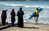 Une surfeuse en tenue de bain entre dans l'eau sur une plage de Rabat, le 1er avril 2018