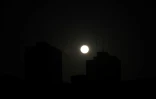 La pleine lune se lève derrière un immeuble de La Havane pendant une panne généralisée d'électricité à Cuba, le 14 mars 2025