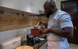 Le chef congolais Archi Dimosi surveille la cuisson d'une sauce dans sa cuisine à Kinshasa, le 17 mai 2026 en RDC