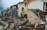 Des pompiers dans les décombres de maisons touchées par une attaque de drones russes dans les environs de Kharkiv, le 21 mai 2024 en Ukraine