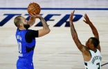 Evan Fournier prend un tir malgré la défense de George Hill de Milwaukee, lors du succès du Magic en playoffs NBA dans la bulle de Disney, le 18 août2020