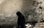 Une Palestinienne passe devant un mur criblé de balles dans le camp de réfugiés de Jénine, en Cisjordanie occupée, le 24 février 2025 