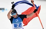 La biathlète française Julia Simon célèbre avec un drapeau à l'arrivée du relais féminin remporté par la France aux Mondiaux de biathlon de Nove Mesto, République Tchèque, le 17 février 2024