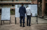 Un policier et un électeur congolais regardent une liste électorale devant un bureau de vote à Kinshasa, le 29 décembre 2018