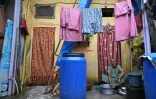 Une habitante, éligible à la relocalisation dans le cadre d'un projet de rénovation urbaine, lave des ustensiles devant son logement du bidonville de Dharavi, le 9 juillet 2025 à Bombay, en Inde