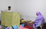 Un commerçant présente un sari traditionnel de Tangail à une cliente dans un magasin, le 2 mars 2026 à Tangail, au Bangladesh