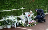 Un policier dépose des fleurs à Magnanville (Yvelines), le 15 juin 2016, après l'assassinat d'un couple de policiers