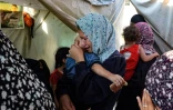 Une femme portant un enfant pleure après une frappe israélienne qui a touché des tentes de déplacés installées dans la cour de l'hôpital des Martyrs d'Al-Aqsa à Deir el-Balah, dans le centre de la bande de Gaza, le 4 août 2024