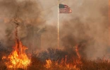 Le drapeau des Etats-Unis flotte au milieu des flammes lors d'un incendie survenu lors d'une vague de chaleur, le 14 juillet 2023 Ă Moreno Valley en Californie, aux Etats-Unis