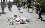 Sous le message "Lâche!" dessiné à la craie, des gens jettent des détritus le 18 juillet 2016 sur la promenade des Anglais à Nice, où un homme conduisant un camion a tué plus de 80 personnes le 14 juillet