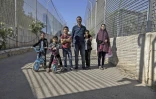 Le Palestinien Saadat Gharib et sa famille dans le corridor grillagé qu'ils doivent emprunter pour entrer et sortir de leur maison encerclée par les logements de colons israéliens, le 19 juillet 2022 à Beit Ijza, en Cisjordanie occupée