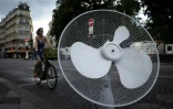 Une cycliste circule près d'un ventilateur abandonné, le 27 juin 2025 à Paris
