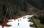 Des personnes s'entraînent à skier sur de la "neige stockée" fabriquée à partir de la neige tombée plus tôt dans les mois d'hiver, à la station de ski de La Bresse-Honeck (Vosges) le 30 décembre 2023