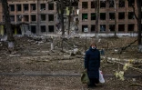 Une femme se tient devant un immeuble détruit après une attaque des forces russes dans la localité ukrainienne de Vasylkiv, près de Kiev, le 27 février 2022