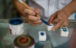 L'artisan Cheung Shun-king peint des tuiles de mah-jong dans son échoppe, le 6 juillet 2022 à Hong Kong