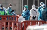 Des passagers en combinaison de protection sont acheminés avec leurs affaires vers un autobus après avoir été évacués du navire de croisière touché par un foyer d'hantavirus, le 10 mai 2026 à Granadilla de Abona, sur l'île espagnole de Tenerife 
