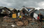 Des habitants devant leurs maisons détruites, à proximité de la digue de Garchitorena, dans la province de Camarines Sur, au sud de Manille, au lendemain du passage du super typhon Fung-wong, le 10 novembre 2025 aux Philippines