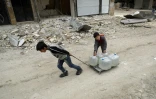 Des enfants tirent des caisses en plastique remplies d'eau dans le quartier de Chaar à Alep, en Syrie, le 9 mars 2017