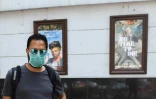 Un homme portant un masque de protection passe devant un cinéma fermé, le 13 mars 2020 à New Delhi, en Inde