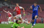 L'attaquant de Leicester Jamie Vardy (d) bute sur le gardien argentin d'Arsenal Emiliano Martinez, sous les yeux du défenseur brésilien David Luiz, le 7 juillet 2020 à Londres