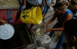 Des habitants du quartier de Petare remplissent des bidons d'eau pour l'utiliser dans leurs toilettes, le 1er avril 2019 à Caracas, au Venezuela